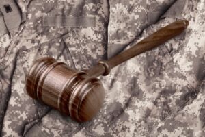The concept of military law, with a soldier and a wooden gavel in a courtroom. 
