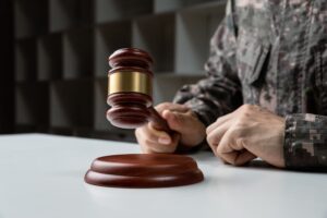The notion of Military Law, depicted through the image of a soldier's hand gripping a gavel.