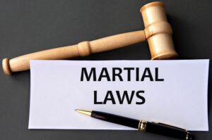 "MARTIAL LAWS" - text on white paper against a dark background with a judge's gavel. Concept of legal information.
