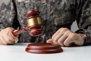 A soldier's hand gripping a gavel in a courtroom symbolizes the concept of military law. 